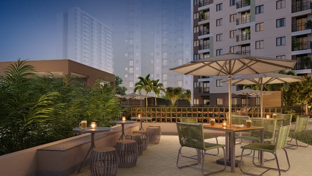 Espaço gourmet externo com mesas, cadeiras e guarda-sóis ao entardecer do Residencial Dona Ivone Lara, no Santo Cristo